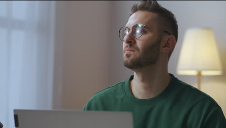 portrait-of-pensive-man-with-glasses-in-front-of-laptop-in-home-writer-of-journalist-is-thinking-freelance-and-creative-job